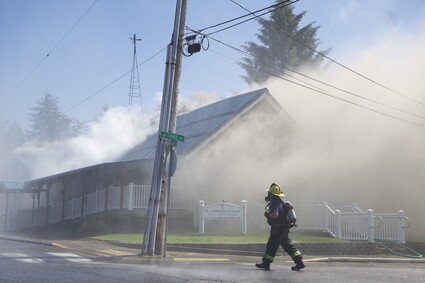 Firefighters spray water onto the roof of St. Catherine of Siena Catholic Church